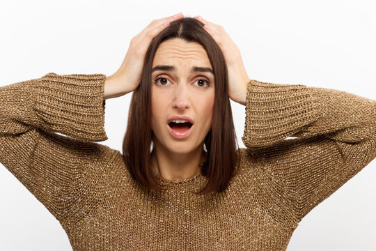 Clueless satisfied young female has spreads hands with hesitation, can not make choice between two nice products, feels doubtful, wears red loose clothes, isolated over white background.