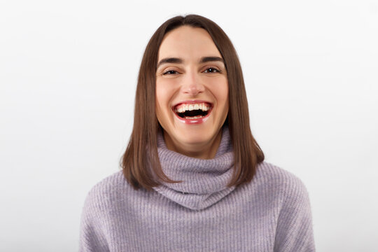 Happy cheerful young woman wearing her brunet hair rejoicing at positive news or birthday gift, looking at camera with joyful and charming smile. Student girl relaxing indoors after college