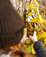 Dziewczynka fotografuje naturę, jest to jesień. Używa do tego telefonu.  © Artur Sobczyk
