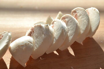 Close-up view of chopped champignons on chopped wooden background. Backstage of cooking homemade spaghetti pasta alla carbonara with cheese and cream sauce. Sunny background. Food concept. Recipe book