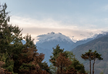 The dramatic peak of Mount Hansling towers above the trees of a forest in the Himalayan village of Munsyari.