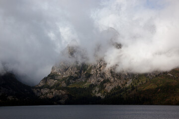Teton mountain with storm clouds and a lake in the foreground