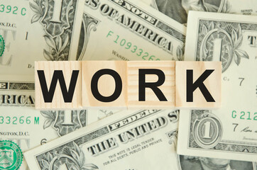 the word work is written on wooden cubes that lie on dollar bills. the concept of unemployment we work hard, live little