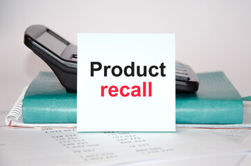 text product recall written on a blue sticker on the back of a notebook and calculator