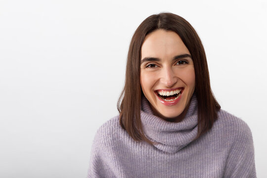 Happy cheerful young woman wearing her brunet hair rejoicing at positive news or birthday gift, looking at camera with joyful and charming smile. Student girl relaxing indoors after college