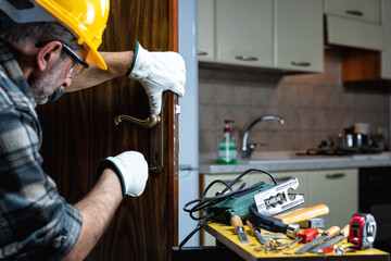 Close-up. Carpenter at work repairs and installs the new lock of a wooden door. Construction...