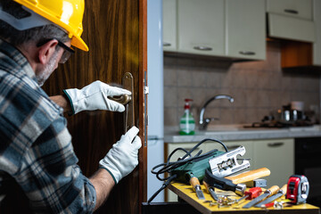 Close-up. Carpenter at work repairs and installs the new lock of a wooden door. Construction...