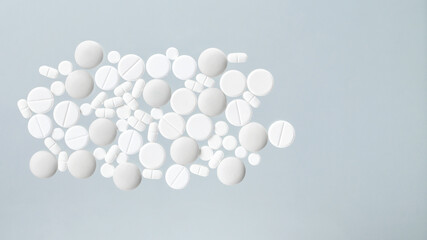 Various white medical pills on blue background