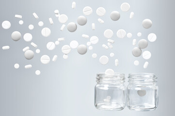 White medical pills fly out of two glass jars
