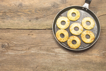 Roasted Pineapple slices in frying pan. Tasty appetizer or side dish to main menu. On old wooden vintage table. Space for text
