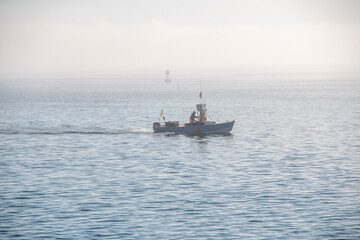 Fisherman’s boat going across the ocean on a foggy day