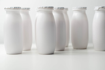 White plastic yogurt bottles on white background, typical packaging for dairy products