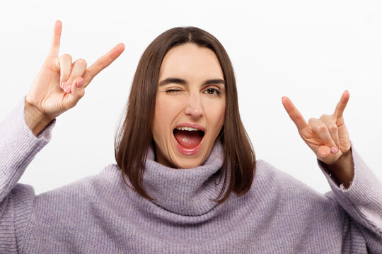 Young beautiful girl wearing casual purple sweater standing over isolated white background shouting with crazy expression doing rock symbol with hands up. Music star. Heavy music concept.