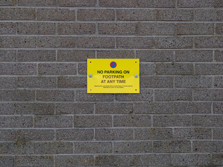 No Parking sign. The sign is mounted on a brick wall and warns not to park on pavement