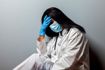 Naklejka premium A stressed out medical worker. Bad news for the patient. Treatment was unsuccessful. Fatigue and frustration during the epidemic. Doctor in a protective mask against the coronavirus COVID-19