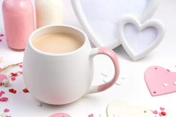 Round mug of coffee with milk on a background of hearts, a white frame and bottles of milk on a white background. Side view. Concept February 14.