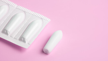 Suppositories for anal or vaginal use on a pink background. Suppositories for the treatment of hemorrhoids, fever, thrush, inflammation. - obrazy, fototapety, plakaty