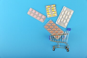 drug purchase concept. pills in supermarket trolley on blue background