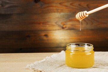 honey dripping from honey dipper into a glass jar