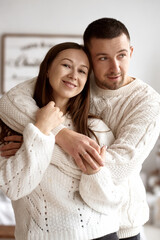 Happy young married couple embracing on the background of a decorated Christmas tree.