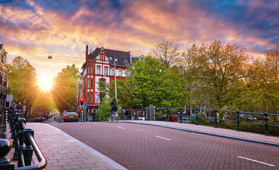 Amsterdam, Netherlands. Panoramic view of autumn Dutch city. Famous channel of Amstel river. Evening cityscape. Colorful sunset scene of famous travel destination in Europe. Romantic traveling place.