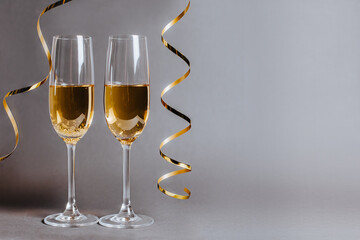 Two glasses of champagne with lights and ribbons on a black gray background holiday