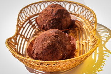 Two delicious handmade chocolates truffle in wickers plate on white background.