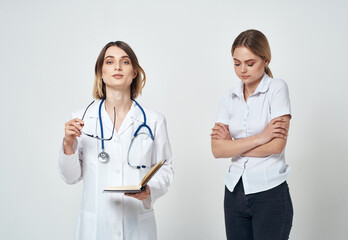 Fototapeta premium Nurse with documents in hands and woman patient on a light background 