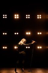 Singer on scene in the club. Bright stage lighting.