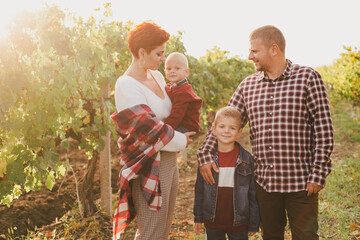 Happy family taking a walk in vineyard at sunset.