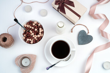 Holiday background with gift box, coffee Cup, cereal plate, ribbon, candles and hearts on a light background. The view from the top. Concept February 14.