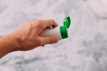 Man holding hand cream tube, close up of his left arm