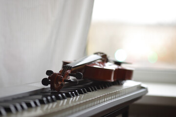 Violin on the keyboard of the electronic piano on the background of the window