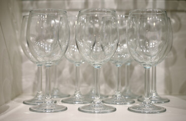 Several transparent glasses on a white shelf