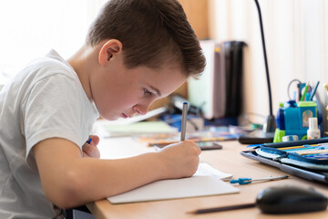 Naklejka premium The boy teaches lessons remotely at home.