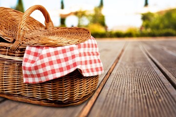 Picnic basket with a tablecloth on a wooden table