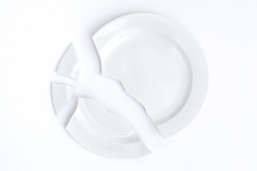 white broken plate on a white background. The concept of destruction, discord