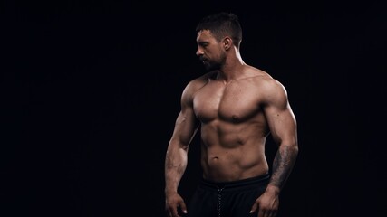 Fototapeta premium Fit and sporty bodybuilder over black background. Sportsman in studio. Sport and fitness concepts.