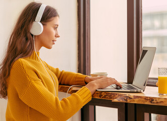 Nice beautiful female with blonde long hair working on laptop sitting at home. Online shoping,...