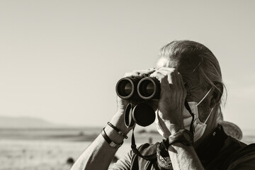 Man with binoculars in the field nature sightseeing travel and tourism