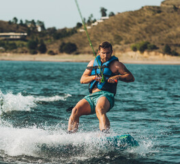 young man doing wakeboarding in a lake whit mountains also doing jumps