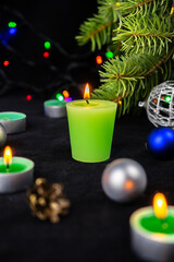 Green candles next to the christmas tree, lights and holiday decoration. Merry Christmas or Happy New Year greeting card.