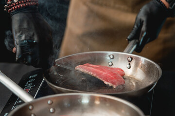 Two frying pans with tuna steak on induction stove