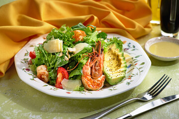 Fresh summer salad with shrimp, avocado and tomato cherry in bowl on light table. Concept of healthy eating.