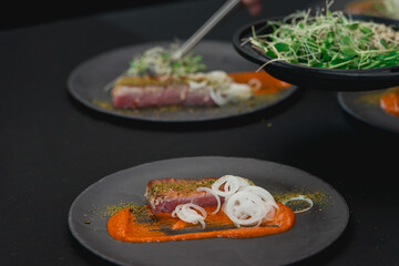 Grilled tuna steak with onion on a grey ceramic plate. Selective focus.
