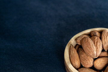 Almonds in a wooden bowl on a black table. Close-up and minimalist shot. top view with copy space for text