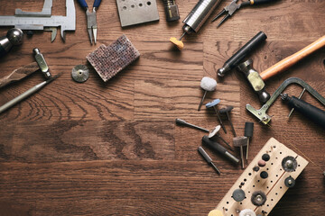 Top view jewelry maker workbench with tools on table. Equipment and tools of a goldsmith on wooden working desk inside a workshop. - obrazy, fototapety, plakaty