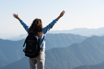 Young woman rising hands against high mountains on background
