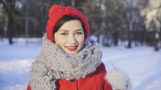 Pretty girl outside enjoying cold snowy winter. Beautiful asian mixed race woman in red winter hat and coat holding christmas wreath and smiling. Merry xmas and happy new year concept.