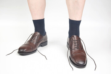 Male legs in socks and brown classic leather shoes on a white background